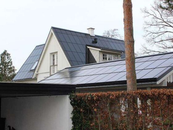 Solcelletag på et hvidt hus, hvor cellerne dækker begge tagflader